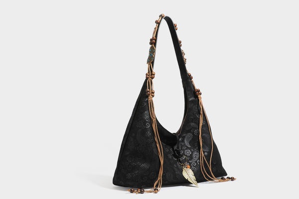 Slouchy boho hobo shoulder bag in embossed brown suede-look finish with beaded strap, cord tassels, and brass-tone leaf