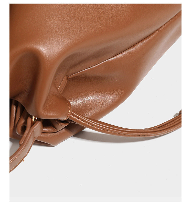 Slouchy ruched drawstring shoulder bag in smooth leather-look finish with gold-tone emblem and slim adjustable strap, detail
