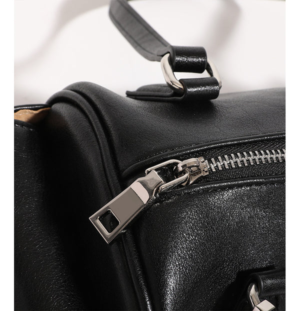 Schwarze Schultertasche in Lederoptik mit zylindrischer Form, silberfarbenen Reißverschlussbeschlägen, zwei flachen Tragegriffen, seitlicher Überschlagtasche und gewebtem Oliv