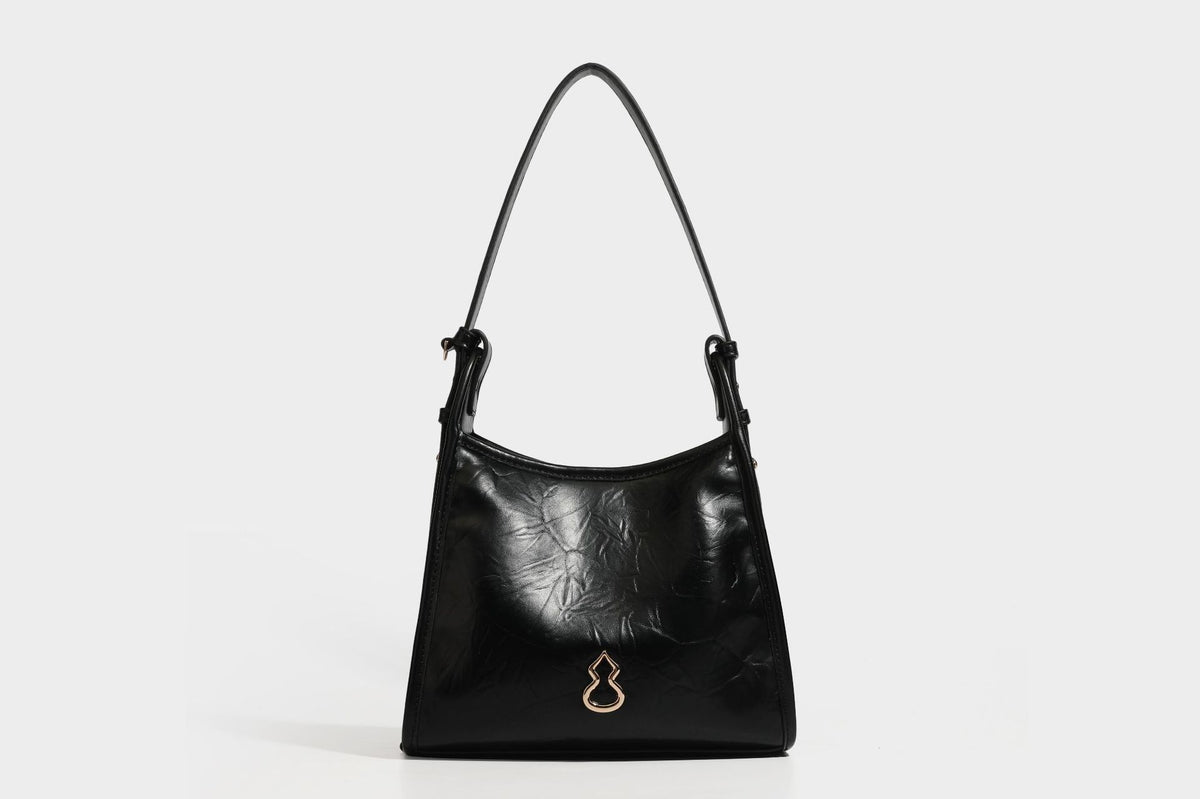 Strukturierte, trapezförmige Schultertasche aus glänzender, geknautscht wirkender Lederoptik mit goldfarbenen Beschlägen auf der Vorderseite und langem, verstellbarem