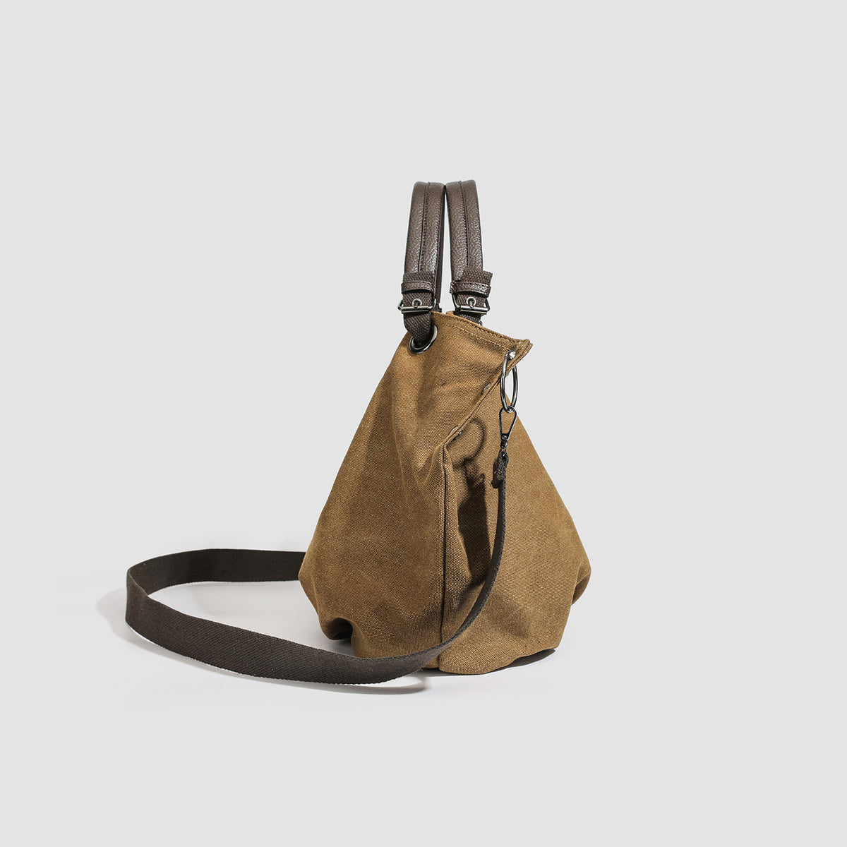 Slouchy matte canvas tote bag with dark dual top handles, metal grommet hardware, and detachable long shoulder strap, detail