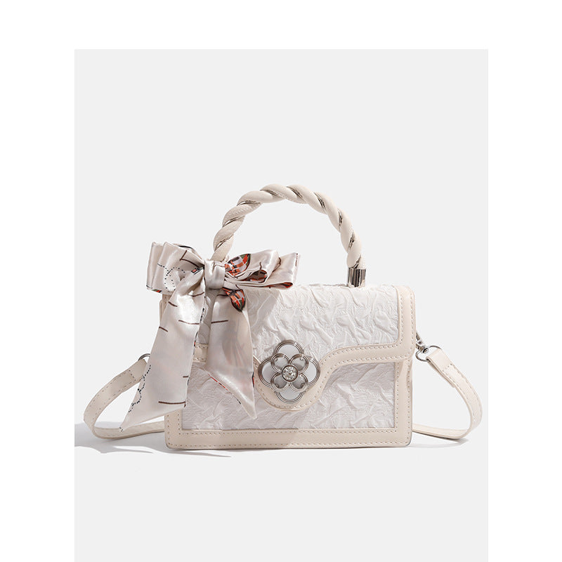 Strukturierte Mini-Crossbody-Tasche in Elfenbein mit geknautschter Oberfläche in Lederoptik, Tragegriff aus einem Seidenschal und silberfarbenem Verschluss in Vierblütenform