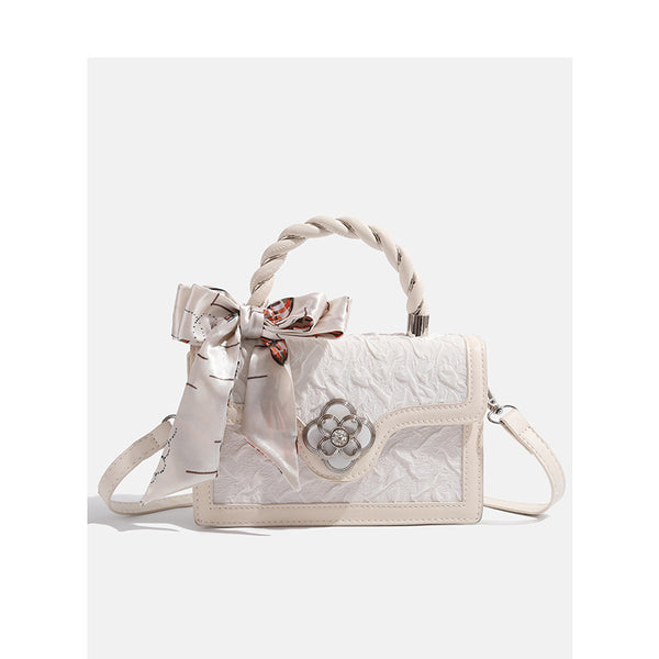 Ivory structured mini crossbody bag with crinkled leather-look finish, silk scarf top handle, silver four-petal flower clasp
