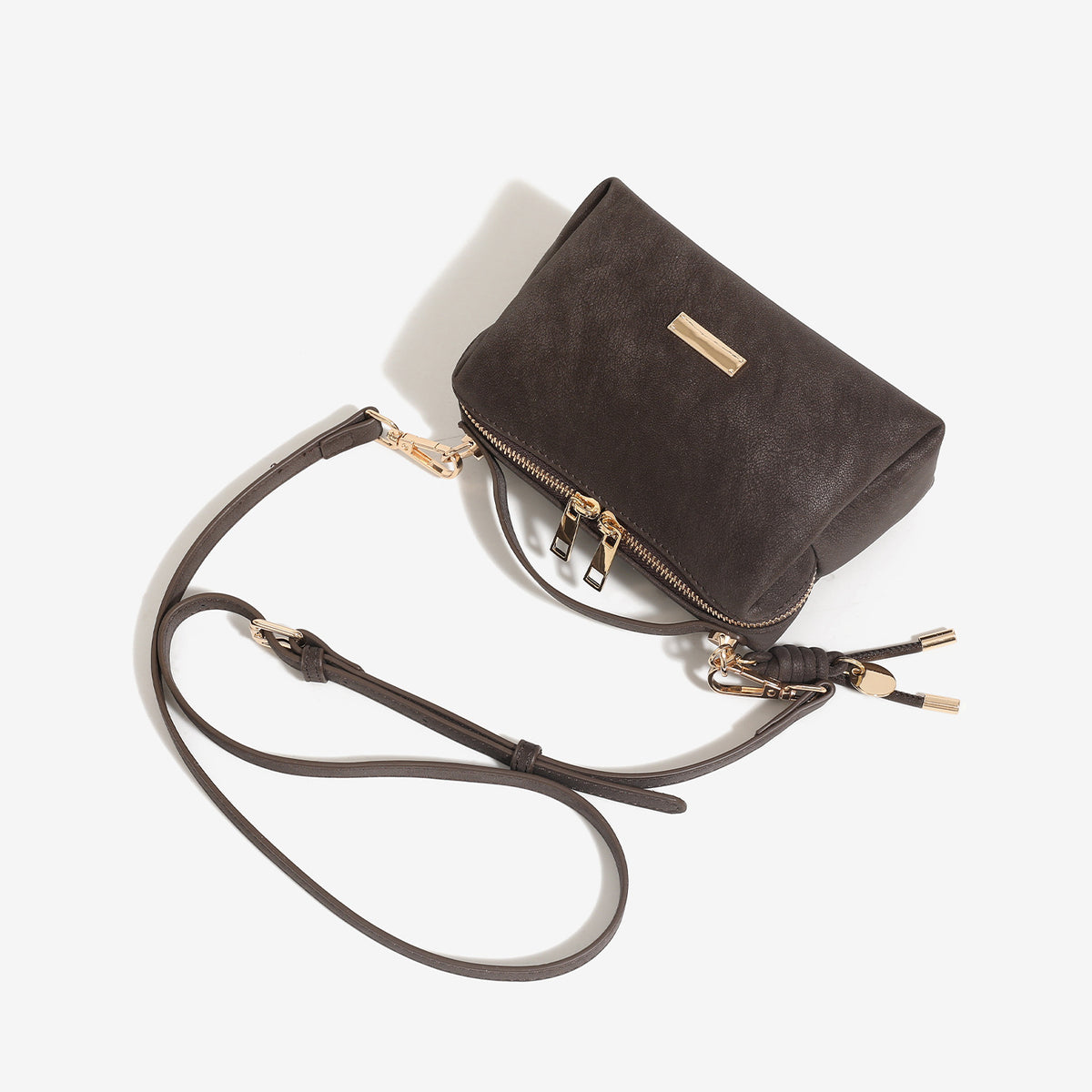 Compact boxy mini handbag with matte pebbled finish, dual top zipper, short top handle, side tassel charm, and gold-tone