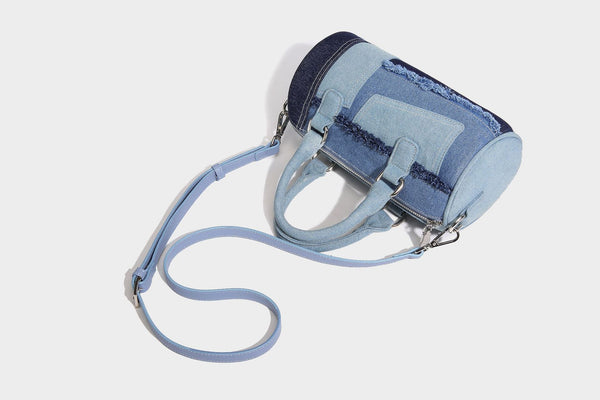 Mini barrel handbag in light and dark denim patchwork with frayed seam trim, dual top handles, top zip closure, and, detail