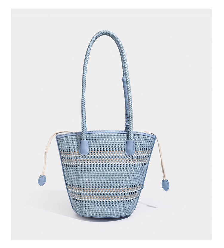 Light blue open-weave woven bucket tote bag with long braided shoulder straps, drawstring side ties, and attached mini pouch