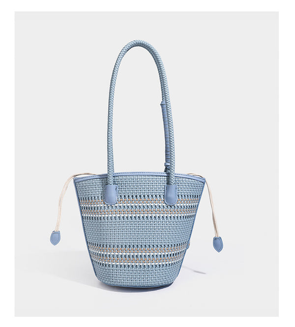 Light blue open-weave woven bucket tote bag with long braided shoulder straps, drawstring side ties, and attached mini pouch