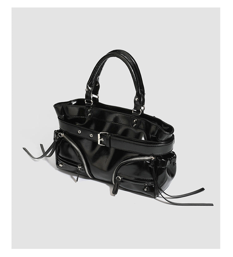 Black glossy structured tote bag with rivet and buckle detail, dual top handles, and detachable shoulder strap, detail view 7
