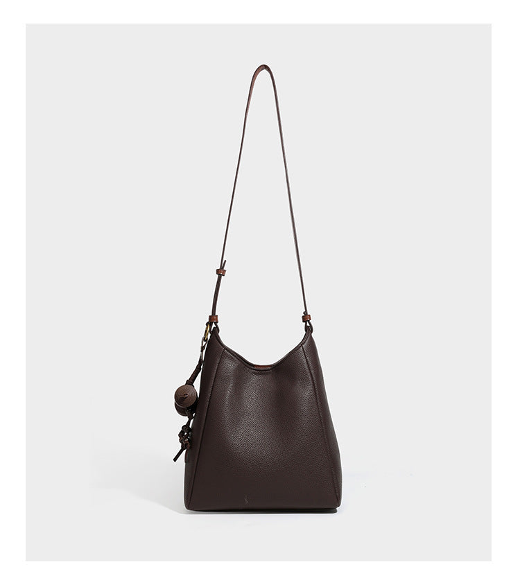 Hobo-Schultertasche in dunklem Espresso mit genarbter Oberfläche, warmen cognacfarbenen Details, verstellbarem schmalem Riemen, goldfarbenen Ringbeschlägen und geknotetem