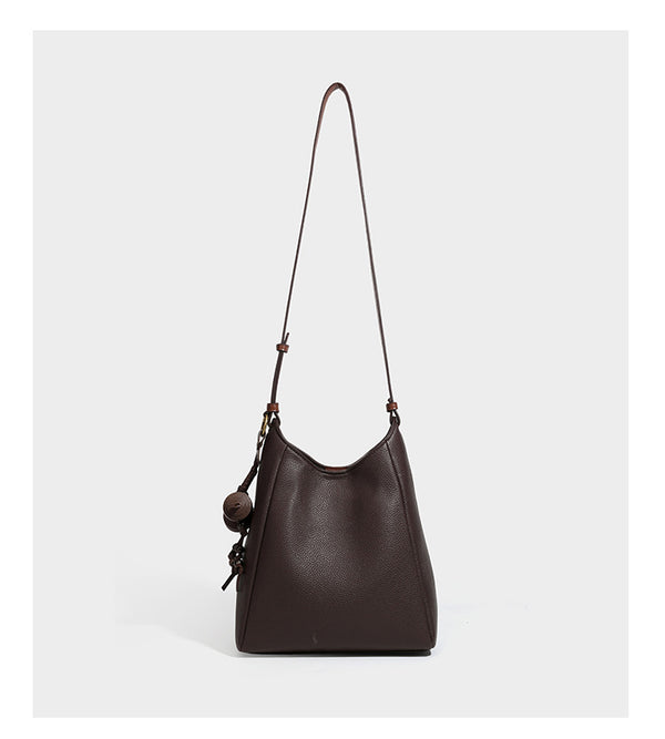 Hobo-Schultertasche in dunklem Espresso mit genarbter Oberfläche, warmen cognacfarbenen Details, verstellbarem schmalem Riemen, goldfarbenen Ringbeschlägen und geknotetem