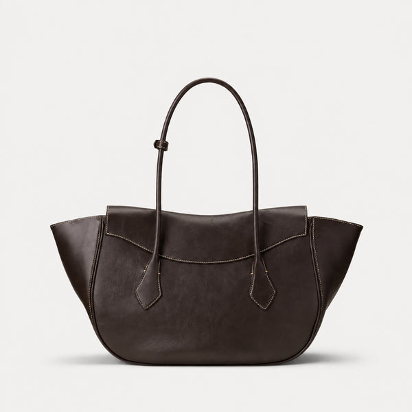 Large winged leather-look tote bag with single arched handle, stitched flap-front panel, and silver ball charm in cognac