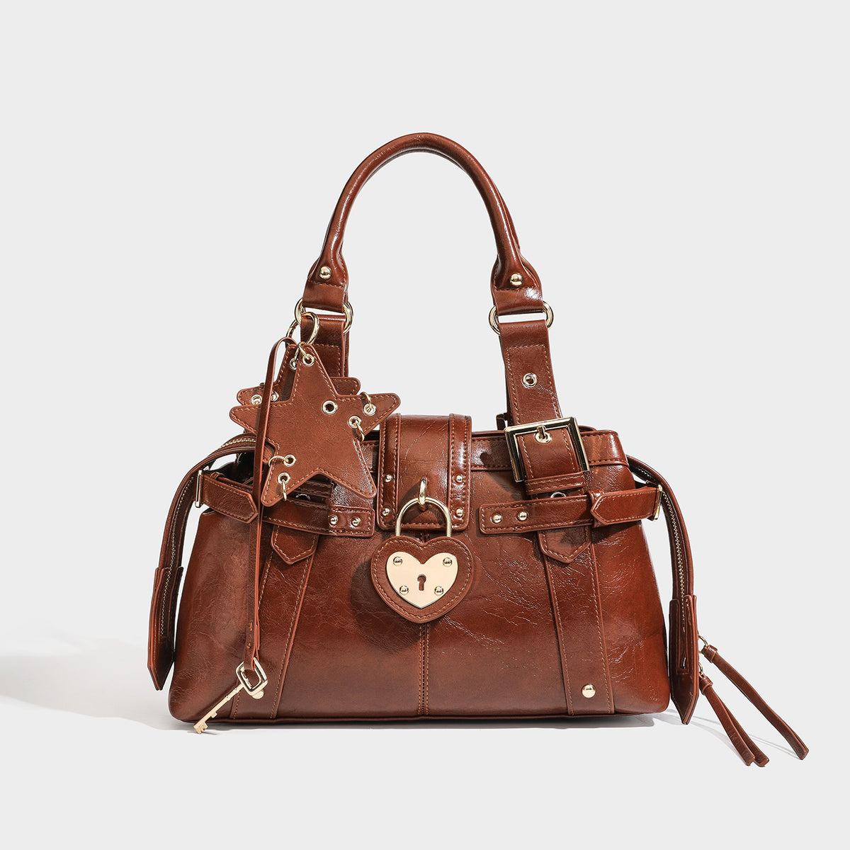 Structured leather-look satchel bag with heart padlock charm, star charm, gold-tone buckle hardware, dual top handles, and