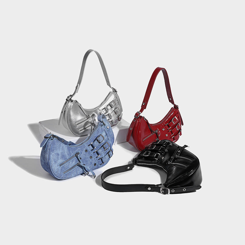 Crescent shoulder bag in washed blue denim-look PU with stacked buckle straps, front zip pocket, and silver-tone hardware