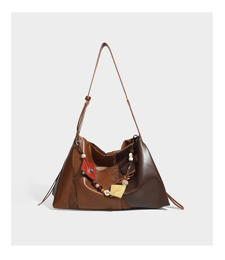 Two-tone black and brown leather-look slouchy shoulder bag with beaded tassel charm and silver-tone hardware, detail view 13