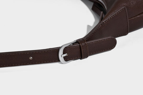 Slouchy bucket hobo shoulder bag in dark brown with glossy leather-look finish, top zip closure, and long adjustable, detail