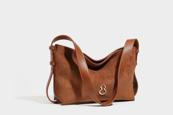 Slouchy suede-finish brown shoulder bag with long single strap and small gold-tone logo emblem on front, detail view 32