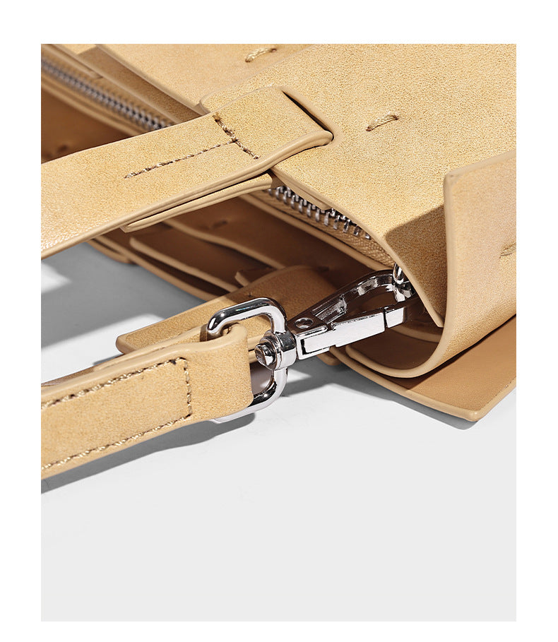 Structured bucket tote bag with vertical panel exterior, dual top handles, and detachable shoulder strap in tan leather-look