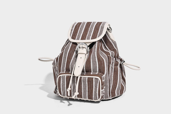 Weicher Rucksack aus gewebtem Material mit vertikalen Streifen, Überschlag, Kordelzug, vorderer Reißverschlusstasche, weißen Besätzen und Trägern in Lederoptik, Detailansicht