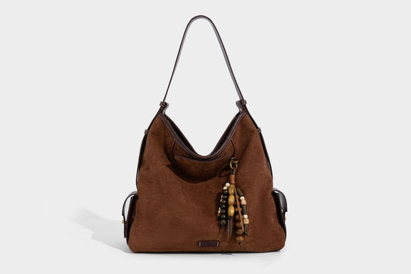 Lässig fallende Hobo-Schultertasche in Khaki aus mattem Material in Wildlederoptik mit dunkelbraunem Besatz in Lederoptik, Quastenanhänger mit Perlen und seitlicher Klappe, Detailansicht