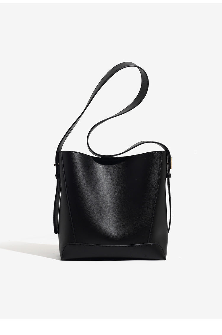 Structured smooth leather-look bucket shoulder bag with long adjustable strap and gold-tone buckle hardware in brown, detail