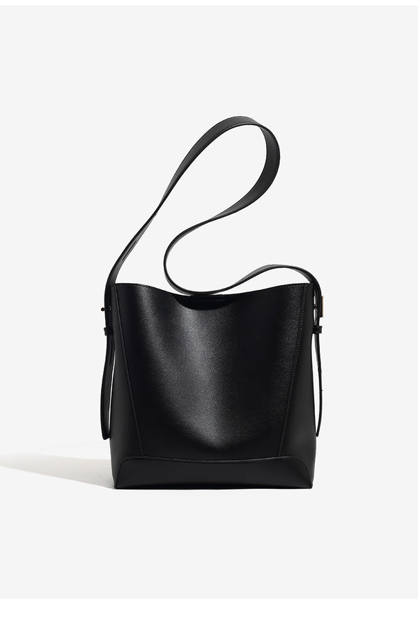 Structured smooth leather-look bucket shoulder bag with long adjustable strap and gold-tone buckle hardware in brown, detail
