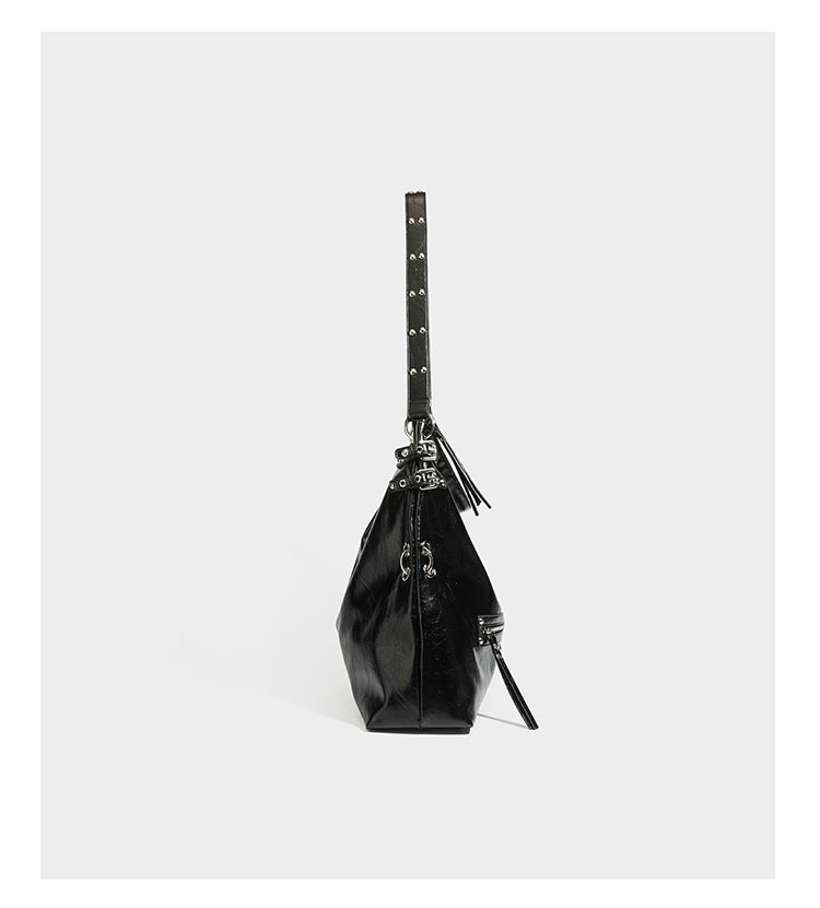 Black glossy leather-look slouchy shoulder bag with silver stud and eyelet hardware, top zip closure, front zip pocket, and