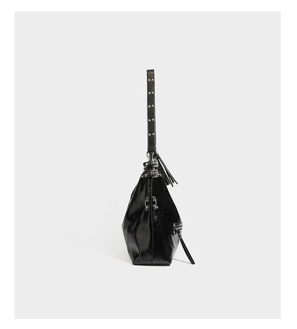 Black glossy leather-look slouchy shoulder bag with silver stud and eyelet hardware, top zip closure, front zip pocket, and