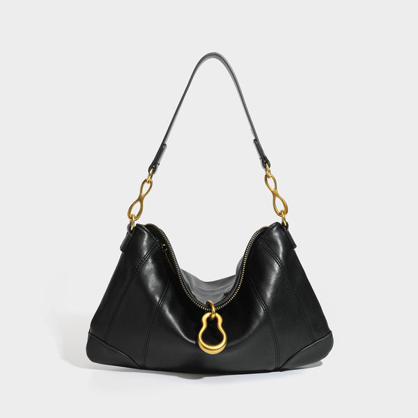Slouchy denim shoulder bag with dark leather-look trim, gold-tone chain-link hardware, and top zipper closure, detail view 4