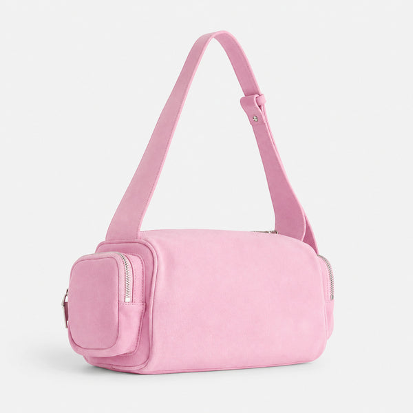 Mini barrel shoulder bag with side zip pouches and adjustable strap in pink suede-like finish, front view
