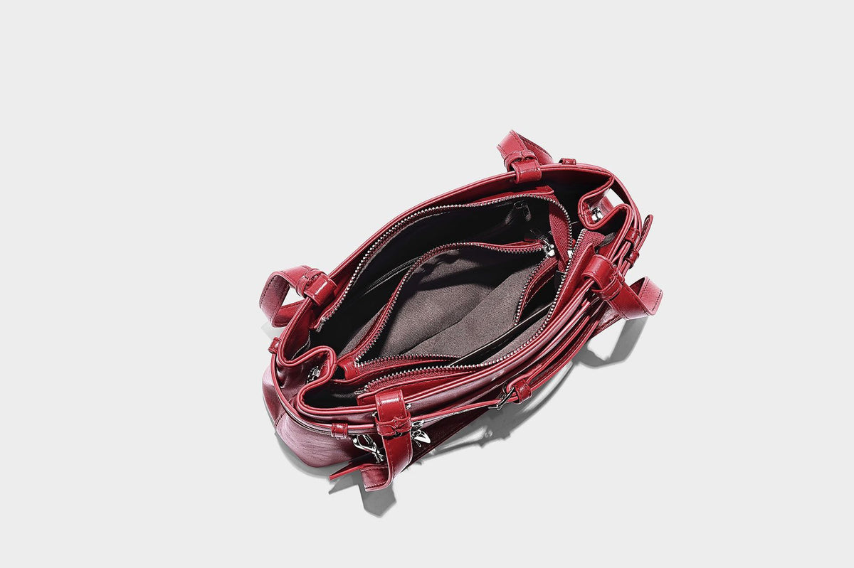 Structured glossy leather-look shoulder bag with wraparound belt straps, silver-tone hardware, and dangling star charm