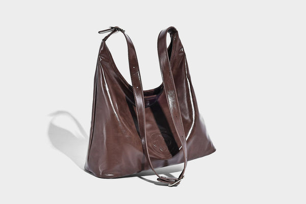Glossy slouchy hobo shoulder bag with adjustable strap and embossed floral emblem, detail view 26