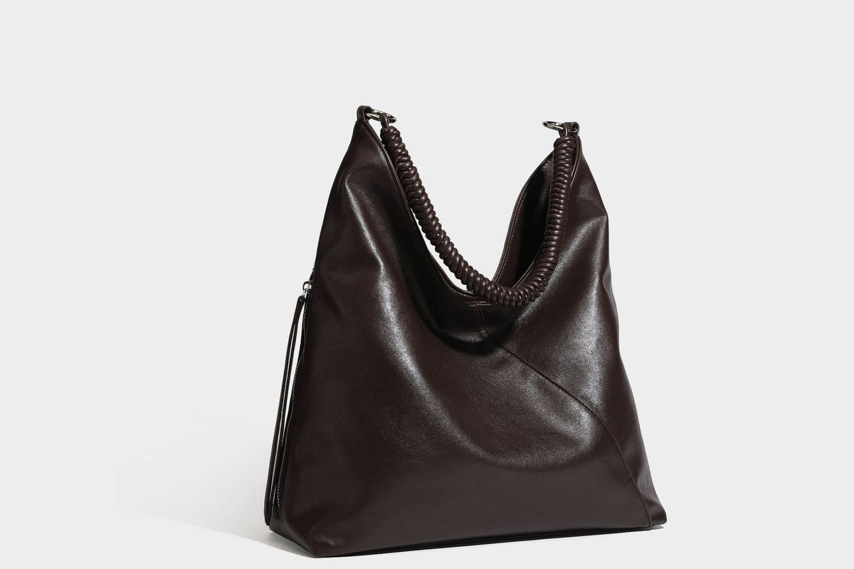Large slouchy hobo shoulder bag with braided top handle, smooth glossy leather-look finish, and silver-tone ring hardware