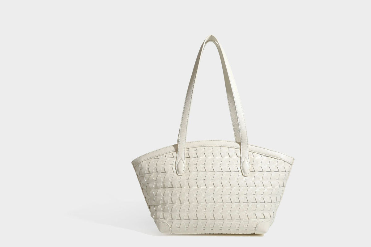 Large leather-look tote bag with geometric woven emboss, double shoulder straps, and round woven cord charm in brown, detail