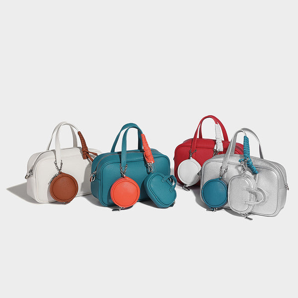 Structured pebbled leather-look Boston bowling bag in tan with blue detachable round mini pouch, dual top handles, and