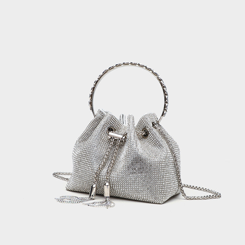 Small all-over rhinestone drawstring bucket bag with jeweled ring top handle and silver chain shoulder strap, front view