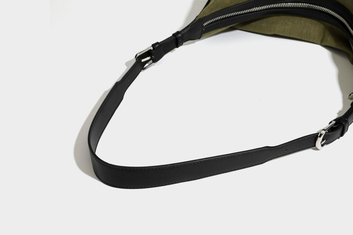 Slouchy olive green canvas hobo shoulder bag with black leather-look trim, zip-top closure, and adjustable strap, detail view