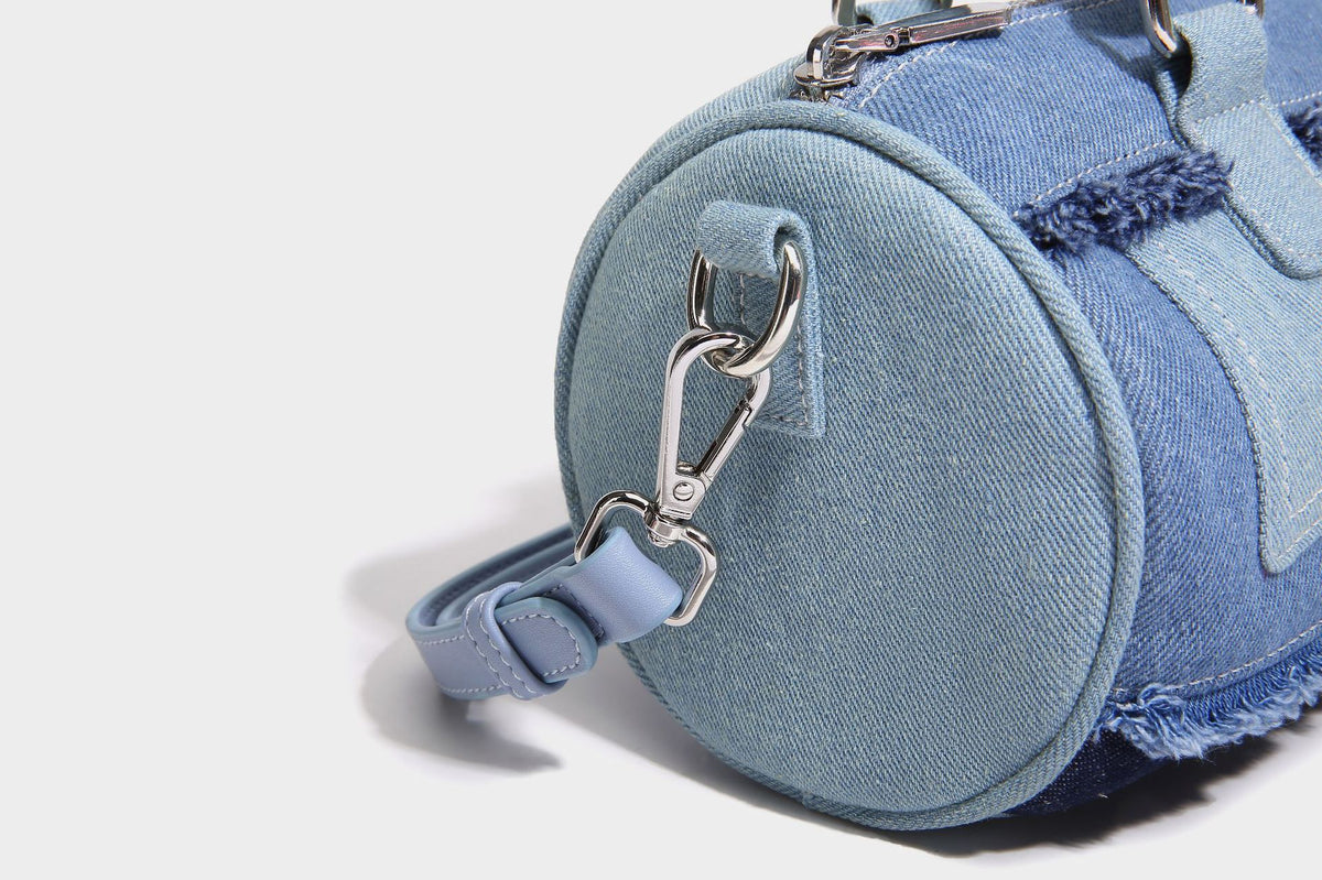 Mini barrel handbag in light and dark denim patchwork with frayed seam trim, dual top handles, top zip closure, and, detail