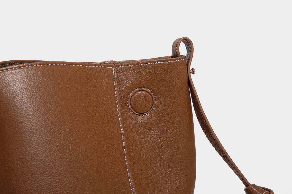 Große, formstabile trapezförmige Tote-Bag aus braunem Lederimitat mit genarbter Oberfläche, zwei Tragegriffen und seitlichen Bindebändern, Detail