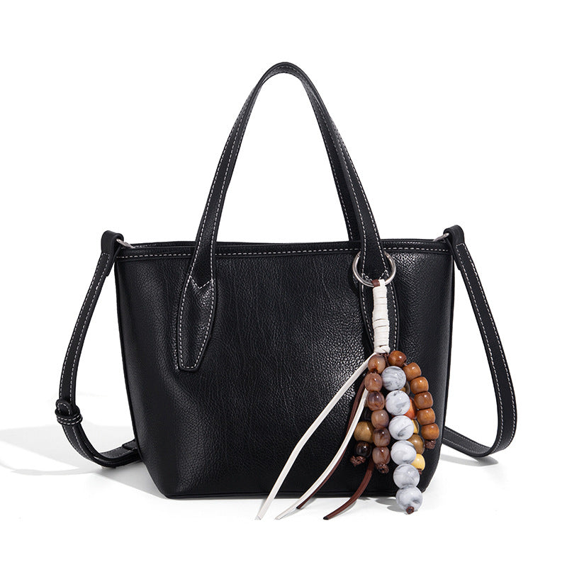 Compact structured bucket tote bag with pebbled textured finish, dual top handles, silver-tone lock hardware, and detachable