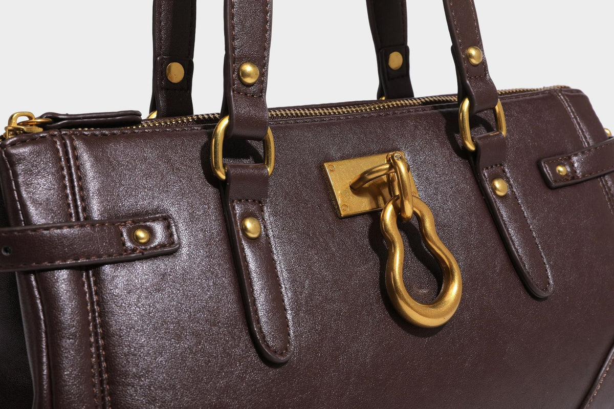 Strukturierte dunkelbraune Satchel-Tote in Lederoptik mit Ringverschluss in Antikgold-Optik, zwei Henkeln und seitlichem Riemen mit Schnalle