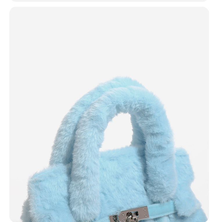 Ice-blue plush faux-fur Kelly-style convertible bag with embroidered smiling face, dark pom-pom feet, silver-tone clasp