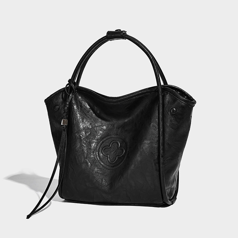 Glänzende Tote-Bag in geknautschter Lederoptik mit geprägtem Rundemblem, Quastenverschluss, zwei Tragegriffen und abnehmbarem