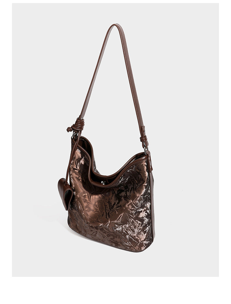 Große Hobo-Schultertasche mit Knitterglanz in Dunkelbraun, schmalem verstellbarem Riemen, geknoteten Metalldetails und seitlich angesetzter Klappe