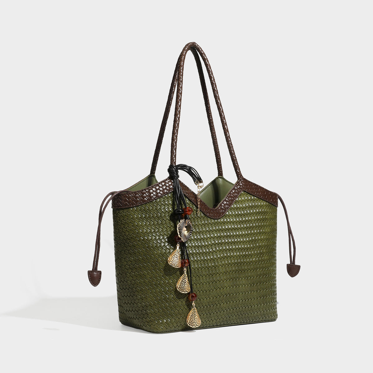 Olivgrüne Tote-Bag in Korbgeflecht-Optik mit dunkelbraunen geflochtenen Schulterriemen, seitlichen Zugbändern und Perlenanhänger in Goldoptik