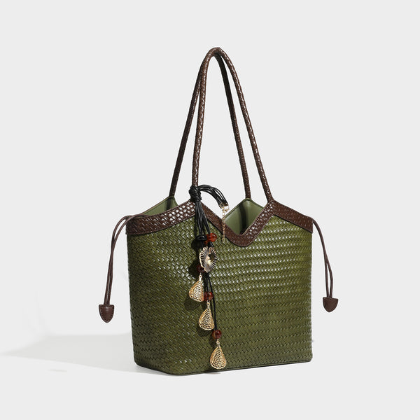 Olivgrüne Tote-Bag in Korbgeflecht-Optik mit dunkelbraunen geflochtenen Schulterriemen, seitlichen Zugbändern und Perlenanhänger in Goldoptik