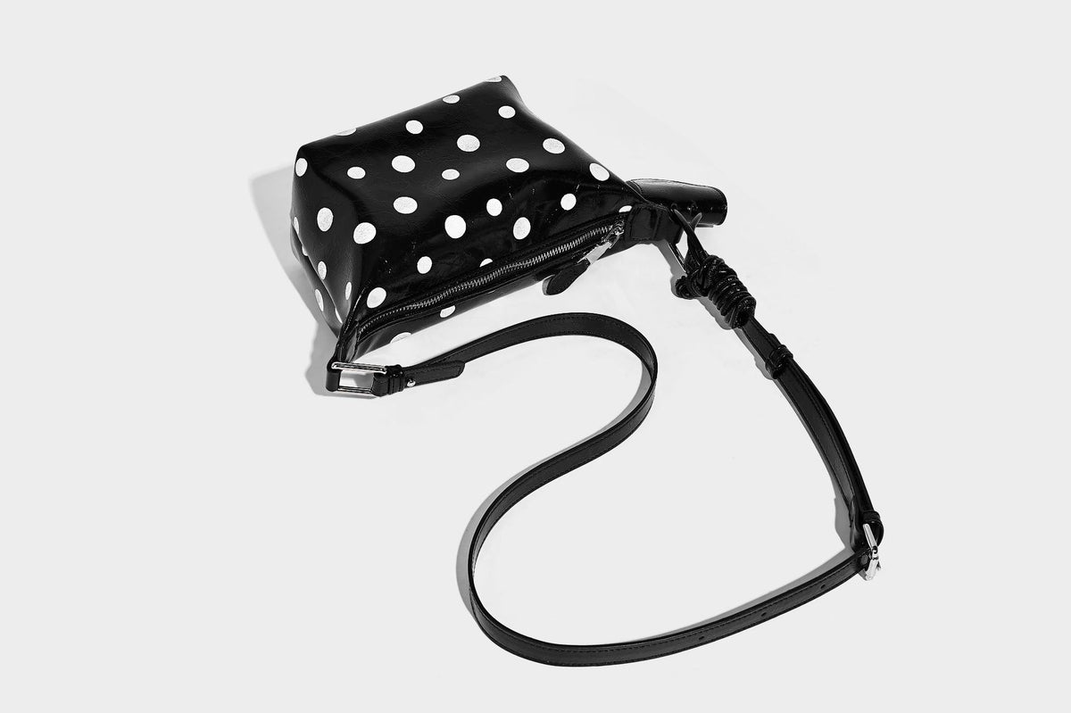 Kompakte glänzende Hobo-Schultertasche in Schwarz mit weißen Punkten, Reißverschluss, Beschlägen in Gunmetal und befestigtem Überschlag vorne