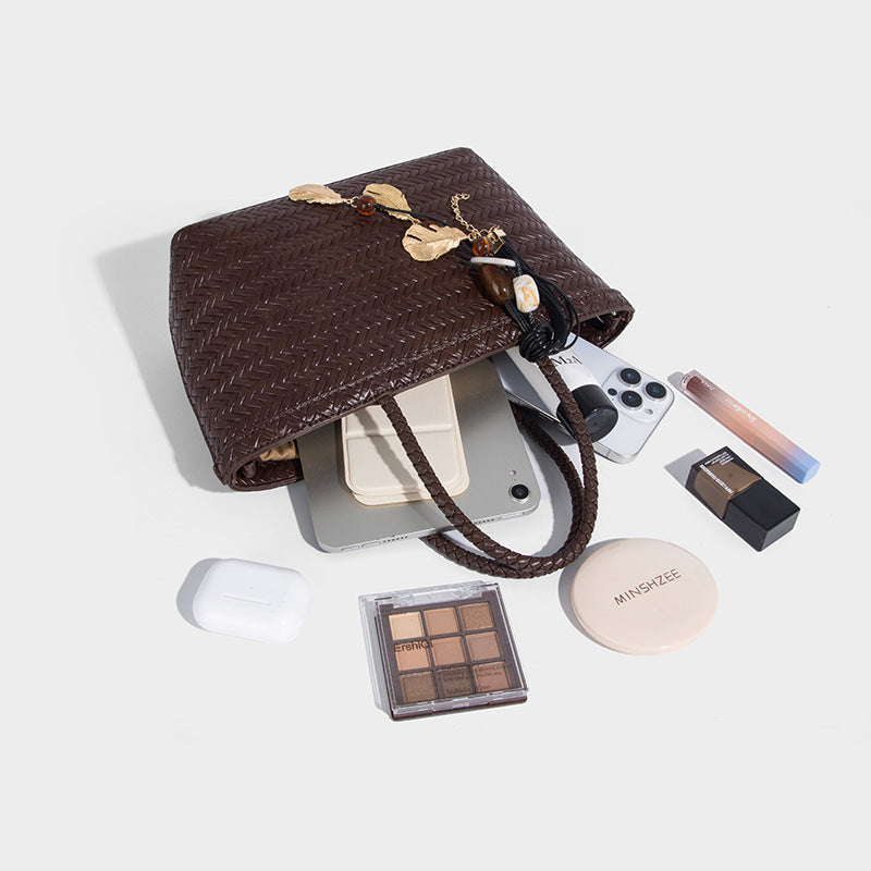 Structured chevron woven leather-look tote bag with braided top handles, gold feather charm, and adjustable shoulder strap