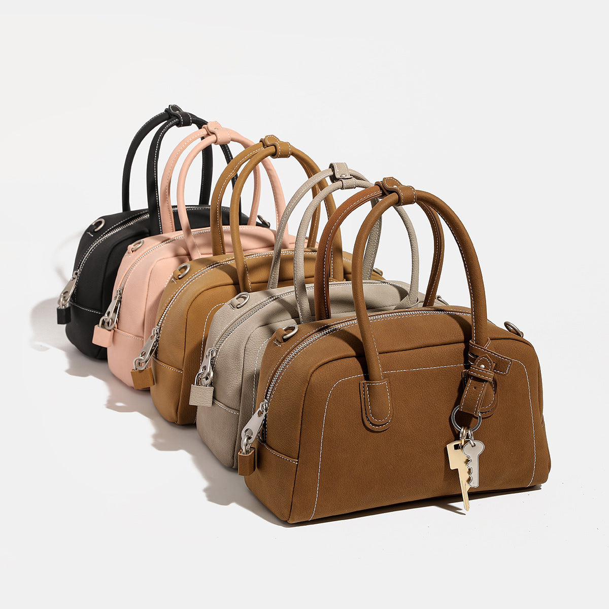 Kompakte, strukturierte Henkeltasche mit matter genarbter Oberfläche, geknoteten Doppelgriffen, goldenem Schlüsselanhänger und abnehmbarem, Detailansicht