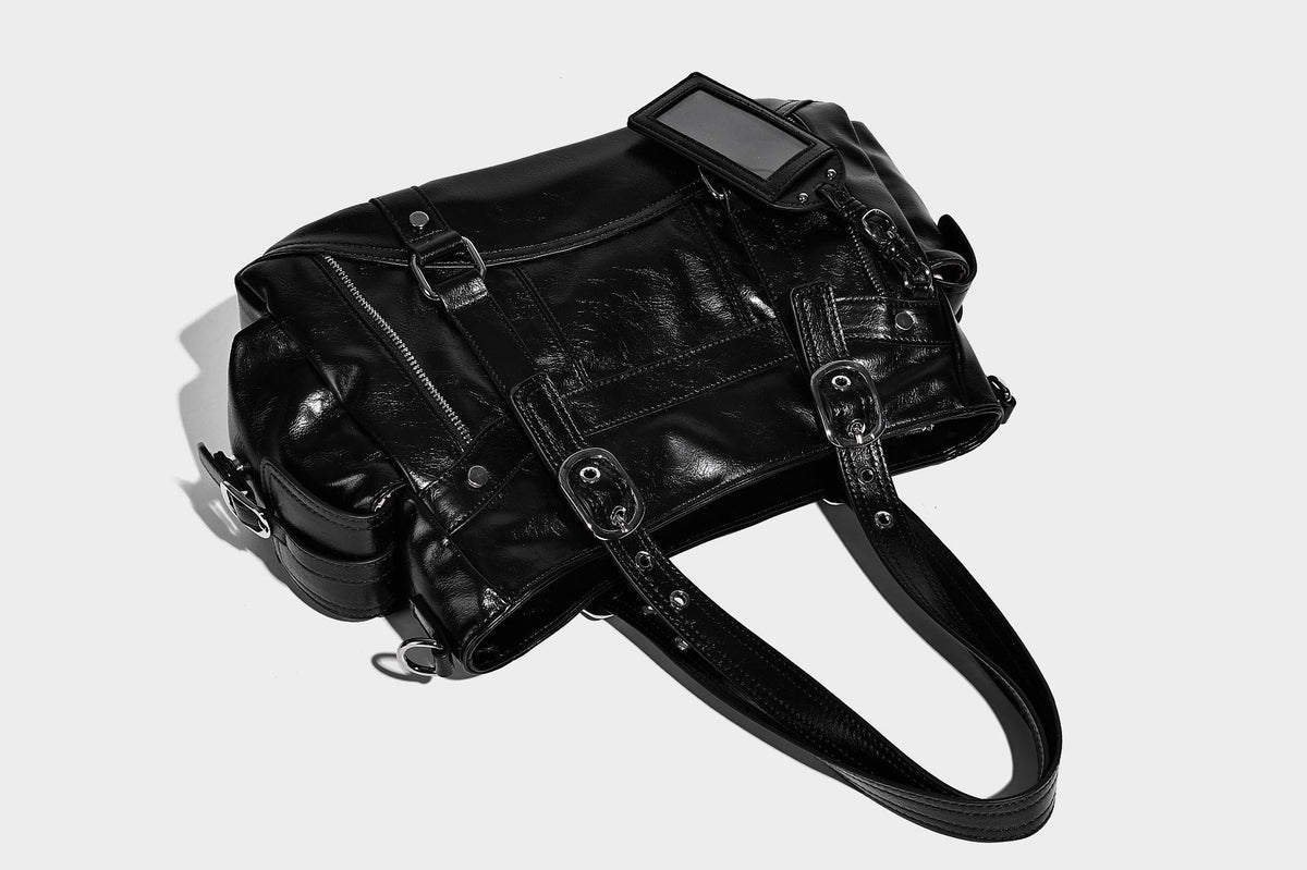 Glossy structured black tote shoulder bag with silver buckle hardware, zip pockets, dual top handles, and detachable, detail