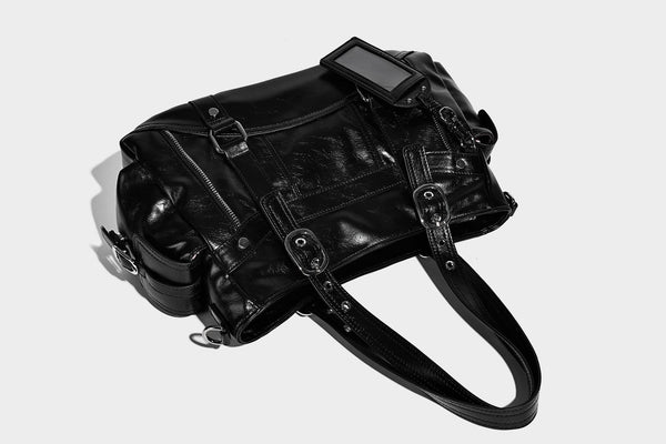 Glossy structured black tote shoulder bag with silver buckle hardware, zip pockets, dual top handles, and detachable, detail